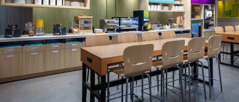 Un restaurant moderne doté d’un bar où l’on sert le petit-déjeuner, de nombreux espaces pour s’asseoir et une variété de buffets proposant différents plats et boissons.