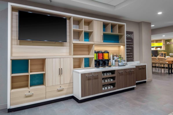 Un área de cocina moderna con armarios empotrados, un televisor de pantalla plana y una estación de café.