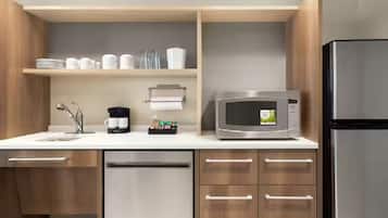 Eine moderne Küche mit einem Edelstahl-Kühlschrank, einer Mikrowelle und einer Kaffeemaschine auf der Arbeitsplatte.