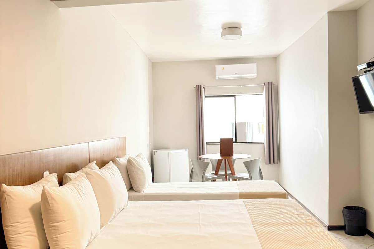 Una habitación de hotel con una cama grande, una mesita y un televisor.