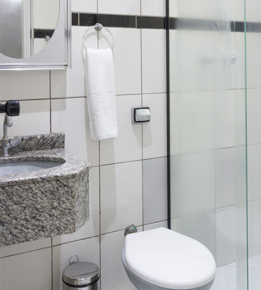 A bathroom with a granite sink, a toilet, and a glass shower enclosure.
