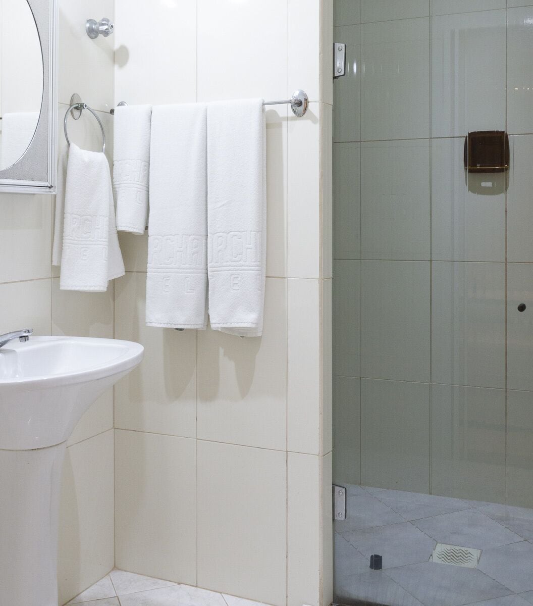 Ein Badezimmer mit Waschbecken, zwei Handtüchern, einem Spiegel und einer Duschkabine.