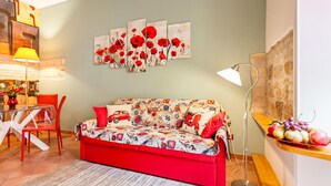 A living room with a red sofa, a glass coffee table, a red chair, a wall-mounted lamp, and a fruit display. - COZY CENTRAL APT CLOSE TO ST PETER BASILICA VATICAN MUSEUMS (Roma)