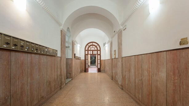 A hallway with wooden paneling, a tiled floor, and a central arched doorway. - COZY CENTRAL APT CLOSE TO ST PETER BASILICA VATICAN MUSEUMS (Roma)