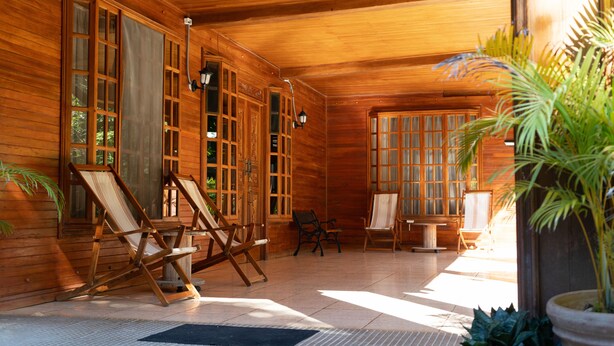 A wooden cabin with large windows, a fireplace, and a seating area with chairs and a table. - Santa Elena Lodge (Santa Elena)