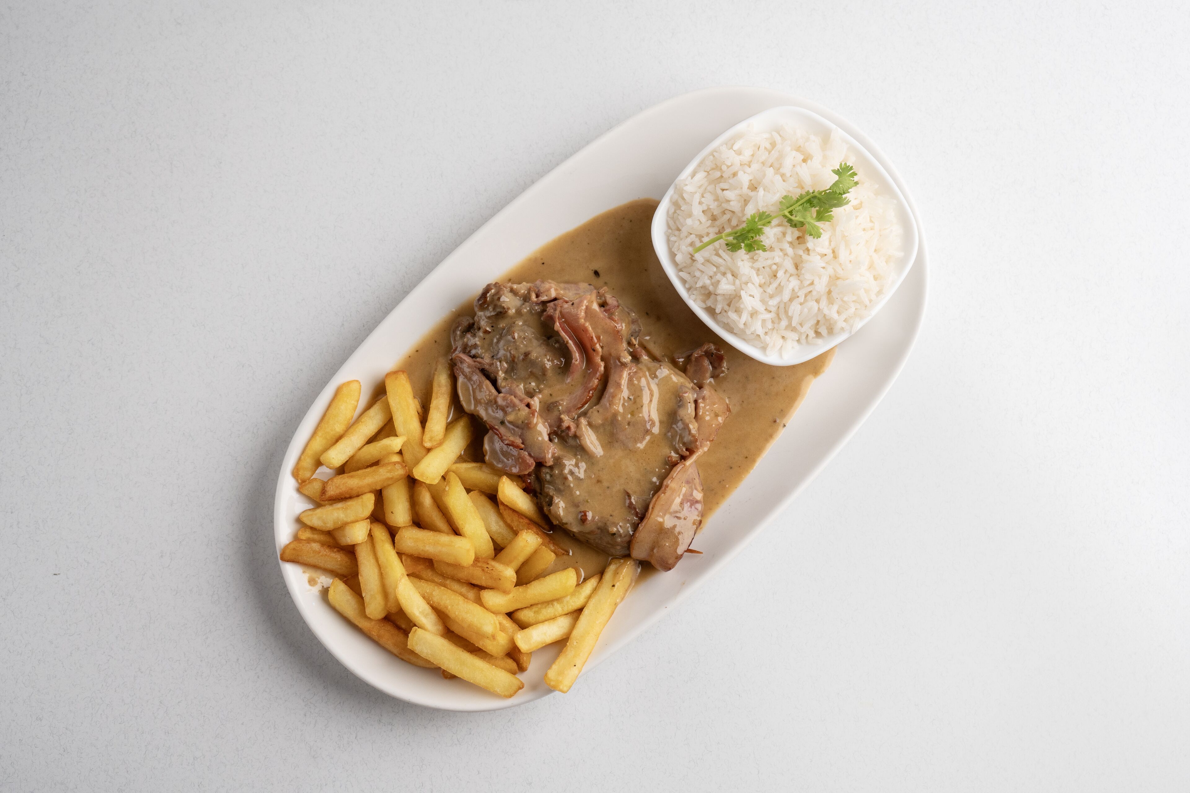 Un plato con un guiso de carne, papas fritas y arroz.