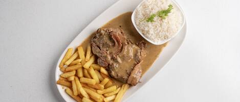 Un plato con un guiso de carne, papas fritas y arroz.