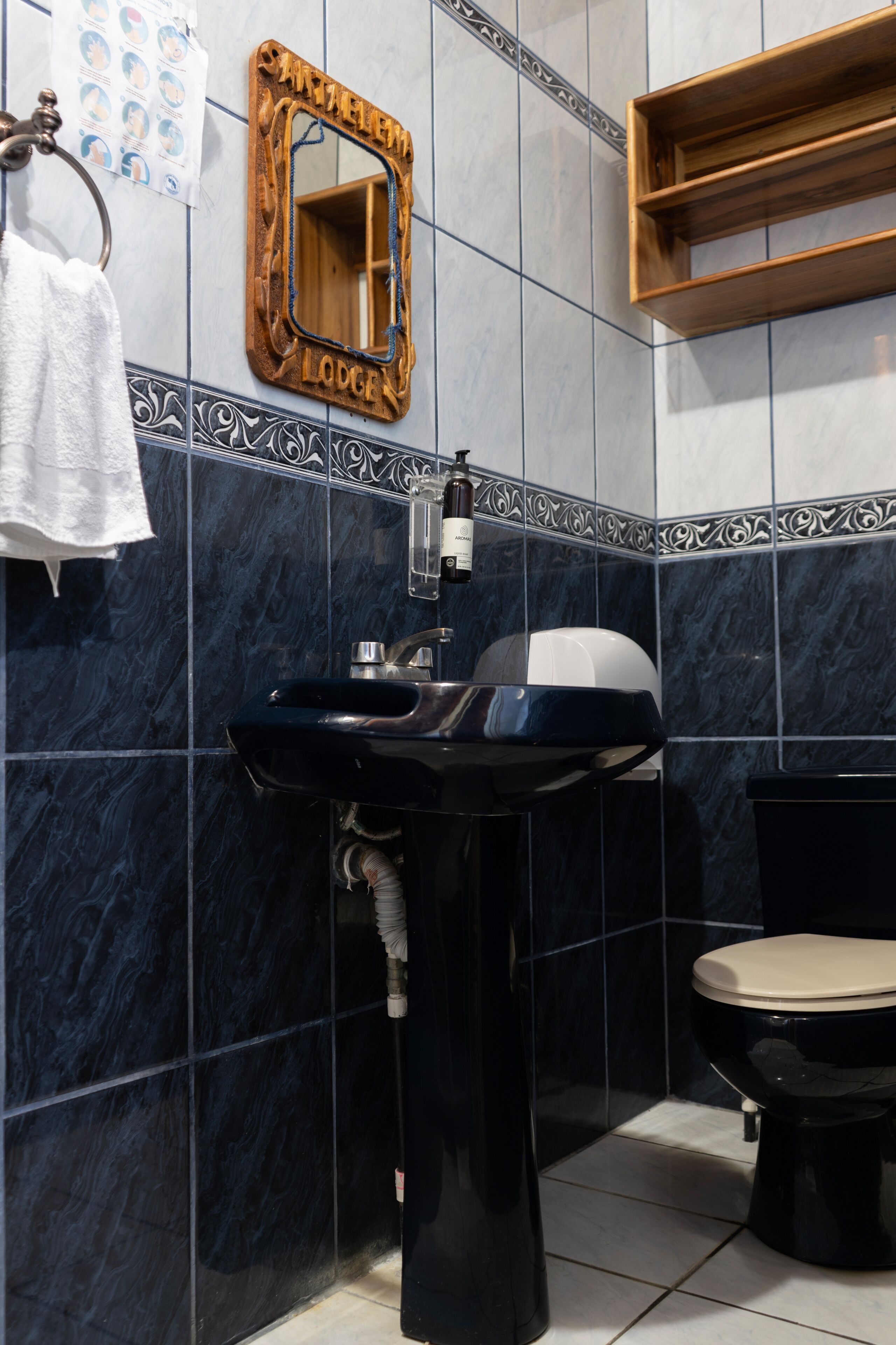 Une salle de bain avec un lavabo noir, un miroir en bois, des toilettes et un porte-serviettes.