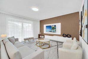 A modern living room with a sofa, a coffee table, and a dining area.