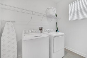 Un espace buanderie comprenant deux machines à laver blanches, un étendoir et un panier à linge.