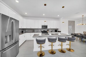 A modern kitchen with white cabinets, stainless steel appliances, and a central island with bar stools.