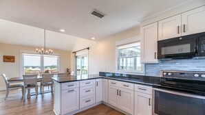 A modern kitchen with white cabinets, a black countertop, and stainless steel appliances.