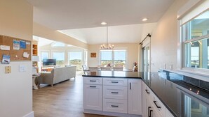 A modern kitchen with white cabinets, a large island, and a view to the outside.