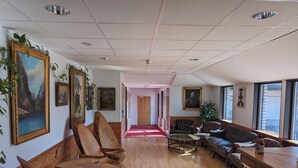 A spacious hallway with wooden benches, a red carpet, and framed artwork on the walls. - Värdshuset Flottaren (Vansbro)