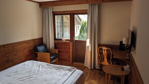 A hotel room with a bed, a wooden desk, a chair, a small table, and a television. - Värdshuset Flottaren (Vansbro)