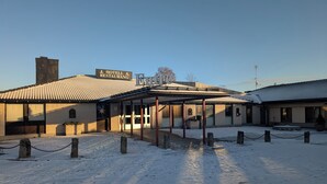 A hotel with a tiled roof, a covered outdoor area, and a snow-covered ground. - Värdshuset Flottaren (Vansbro)
