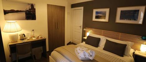 A hotel room with a bed, a desk, a chair, a lamp, and a wall-mounted air conditioner.