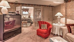 Een woonkamer met een rode fauteuil, een bank, een televisie en een kleine tafel met een lamp.