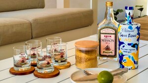A white table with a bottle of rum, a can of rum, a lime, and several shot glasses. - Kay Alice - Beachfront Villa (Le Carbet)