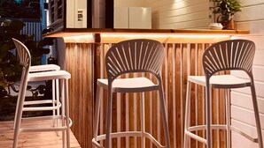 An outdoor bar area with wooden flooring and metal chairs. - Kay Alice - Beachfront Villa (Le Carbet)