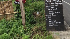 A signboard listing Melody Warung's offerings including foods, beverages, and activities like surf lessons and tours. - Melody (Jerowaru)
