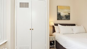 Ein Schlafzimmer mit Bett, Nachttisch, Lampe, Kleiderschrank und einem Bild an der Wand.
