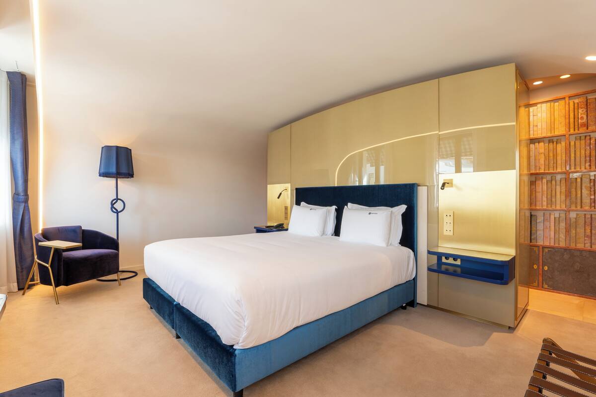 Een moderne hotelkamer met een groot bed, een bureau, een stoel en een boekenplank.