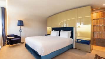 Una habitación de hotel moderna con una cama grande, un escritorio, una silla y una estantería.