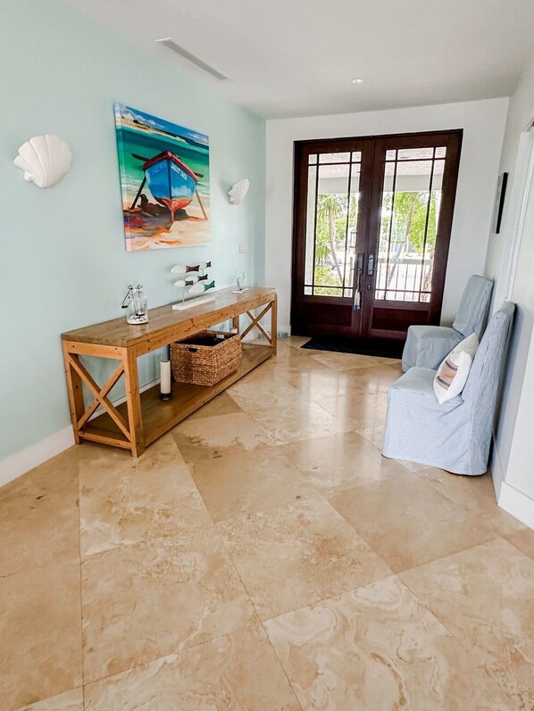 A spacious living area with a wooden console table, a comfortable armchair, and a large window with a view of greenery.