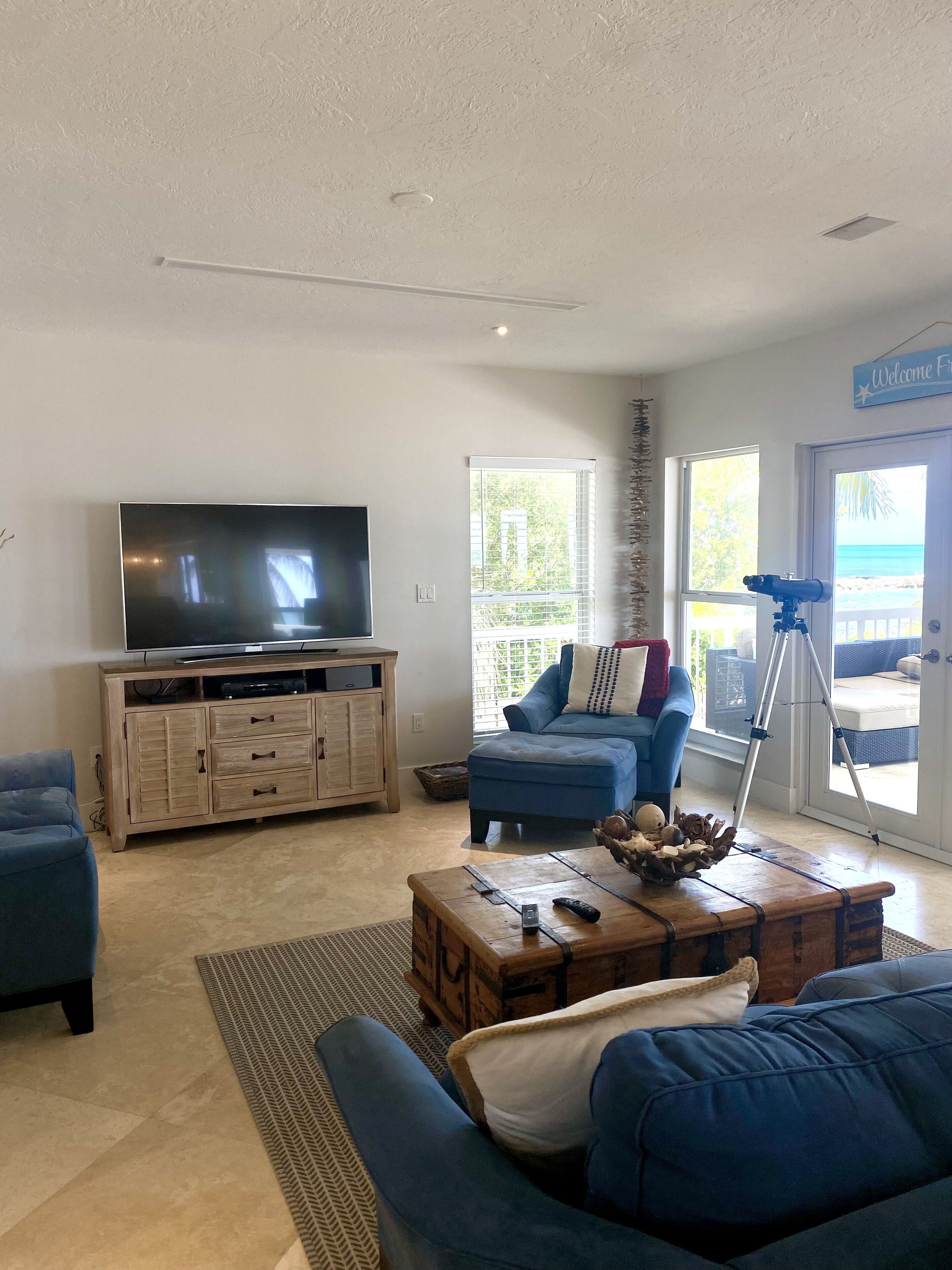Ein Wohnzimmer mit Fernseher, blauem Sofa, Holzschrank und einem Teleskop auf einem Stativ.