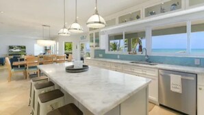 A modern kitchen with a large island, pendant lighting, and a view of the ocean. - Keys home overlooking the ocean and beautiful sunrises! (Islamorada)