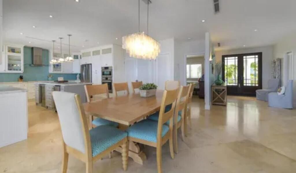 A spacious kitchen with modern appliances, a dining area with a wooden table and chairs, and a bright pendant light.