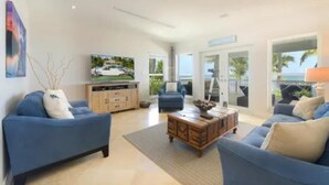 A modern living room with blue sofas, a wooden coffee table, and a flat-screen TV. - Keys home overlooking the ocean and beautiful sunrises! (Islamorada)