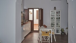 Una cucina con mobili in legno, un tavolo da pranzo bianco con sedie gialle e un pensile con ante in vetro.
