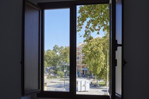 Una habitación con un ventanal que ofrece vistas a una calle y edificios de la ciudad.