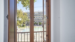 Vista da un balcone con ringhiera in metallo, su una piscina e un edificio sullo sfondo con diversi balconi.