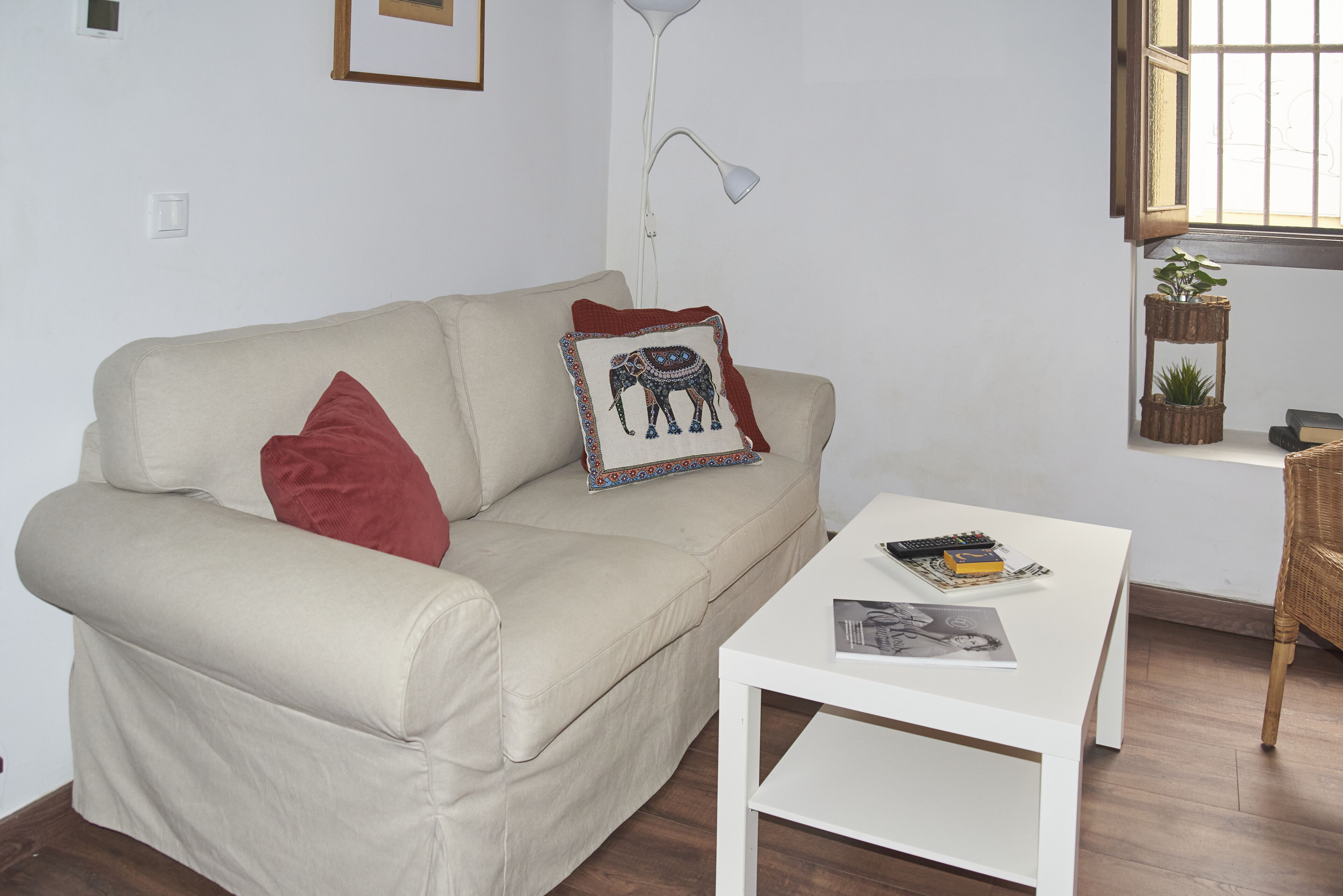 Un salon avec un canapé beige, une table basse blanche et un lampadaire.