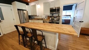 A kitchen with a wooden island, stainless steel appliances, and white cabinetry.
