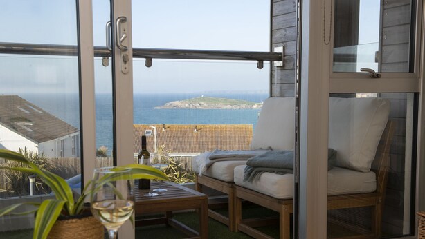 Un balcon avec vue sur la mer, un canapé, une table avec un verre à vin et une plante en pot.