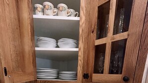 Een keuken met houten kastjes, een betegelde spatwand en een aanrecht met verschillende pannen.
