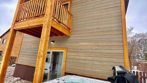 Een houten chalet met balkon, een bubbelbad en een houten terras.
