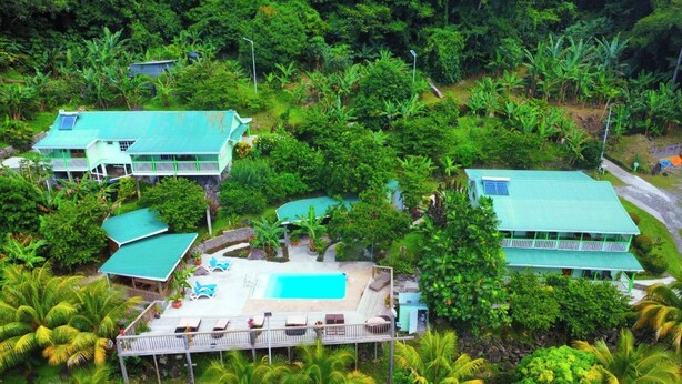 A resort with multiple buildings, a swimming pool, and lush tropical vegetation. - Pinard's Mountain Resort- Cottage 9 (Pointe Michel)