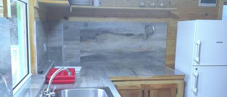 A kitchen with a gas stove, stainless steel sink, wooden cabinets, and a white refrigerator.