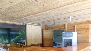 A wooden interior with a kitchen area, including a refrigerator, wooden cabinets, and a television. - Pinard's Mountain Resort- Cottage 9 (Pointe Michel)