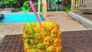 A pineapple with straws on a woven table in an outdoor setting.