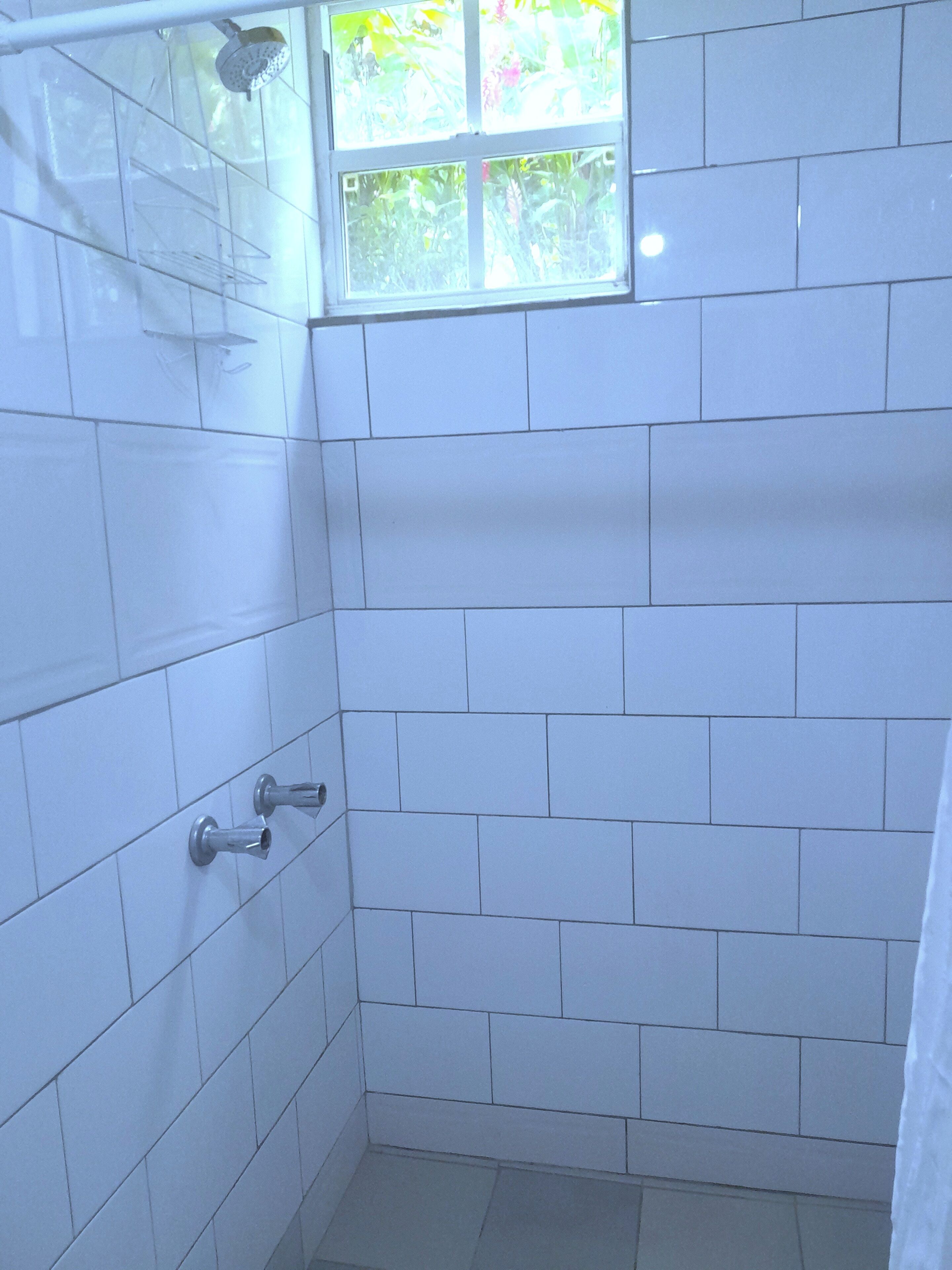 A small, tiled shower area with a window above the showerhead.