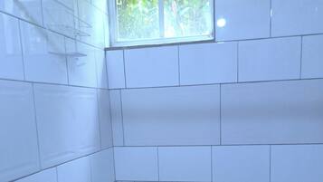 A small, tiled shower area with a window above the showerhead.