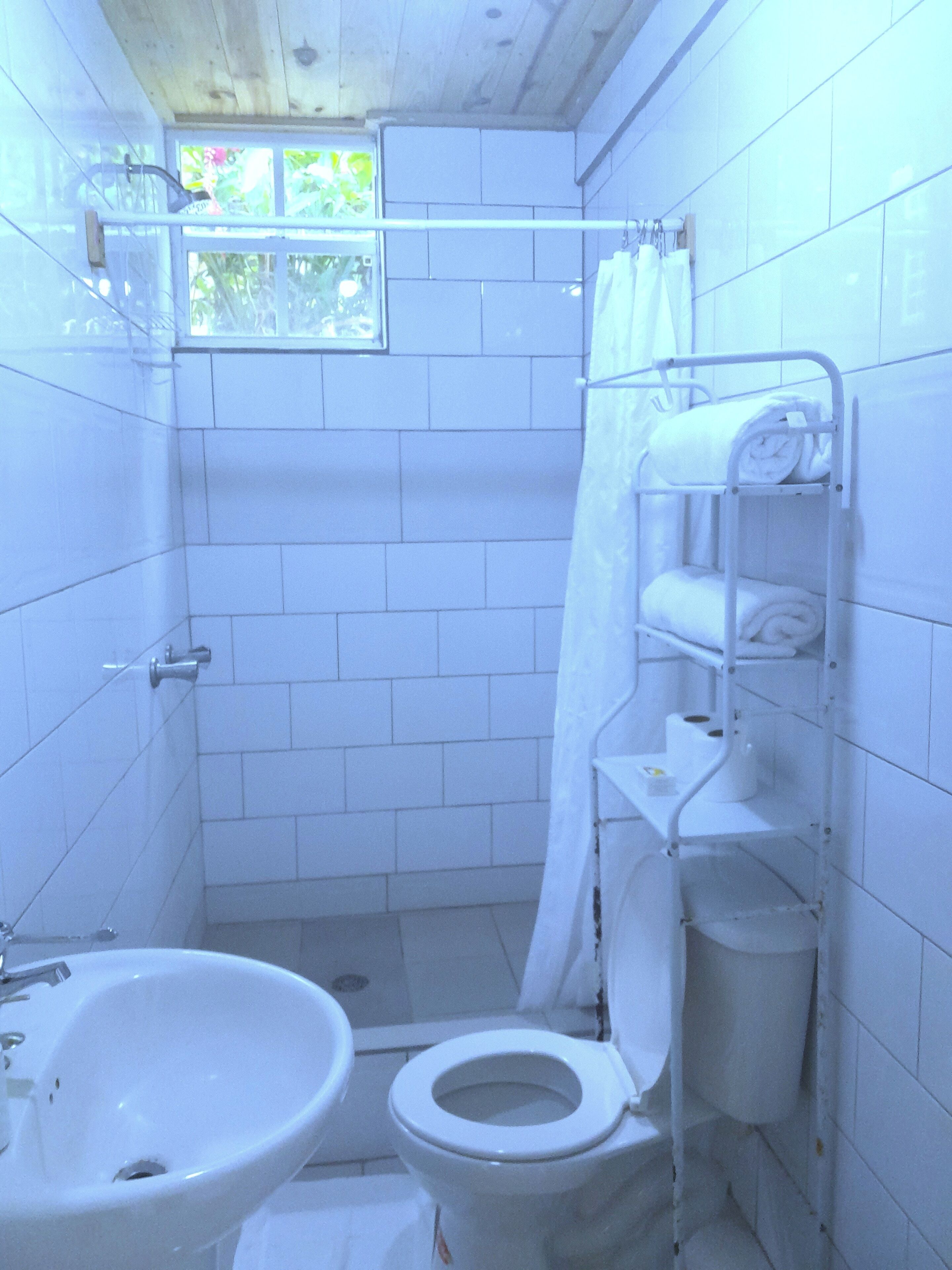 A small, tiled bathroom with a toilet, sink, and shower.