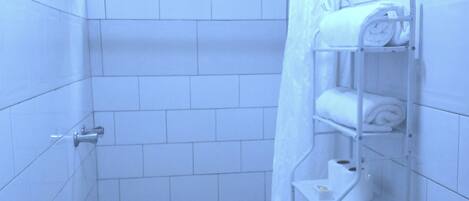A small, tiled bathroom with a toilet, sink, and shower.