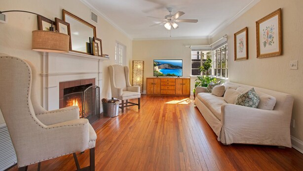 A living room with a fireplace, a television, a sofa, and a ceiling fan. - Home away from home in the heart of charming Winter Park! (Winter Park)